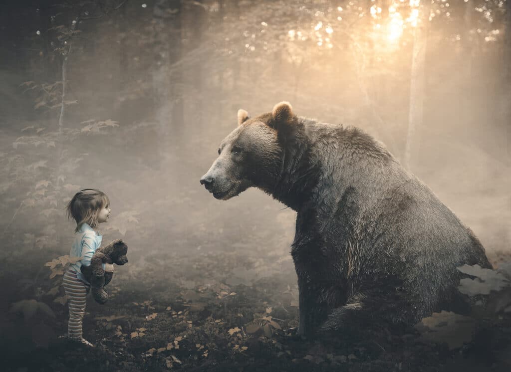 Ein Mädchen mit einem lieben Bär im Arm trifft einen echten Bären im Wald.