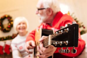 selective focus of senior couple with acoustic guitar at christmas eve